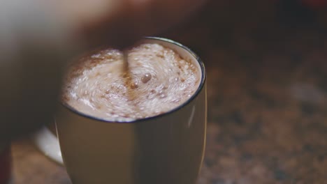 warme chocolademelk in een mok die wordt geroerd met een theelepel voor het ontbijt - close-up