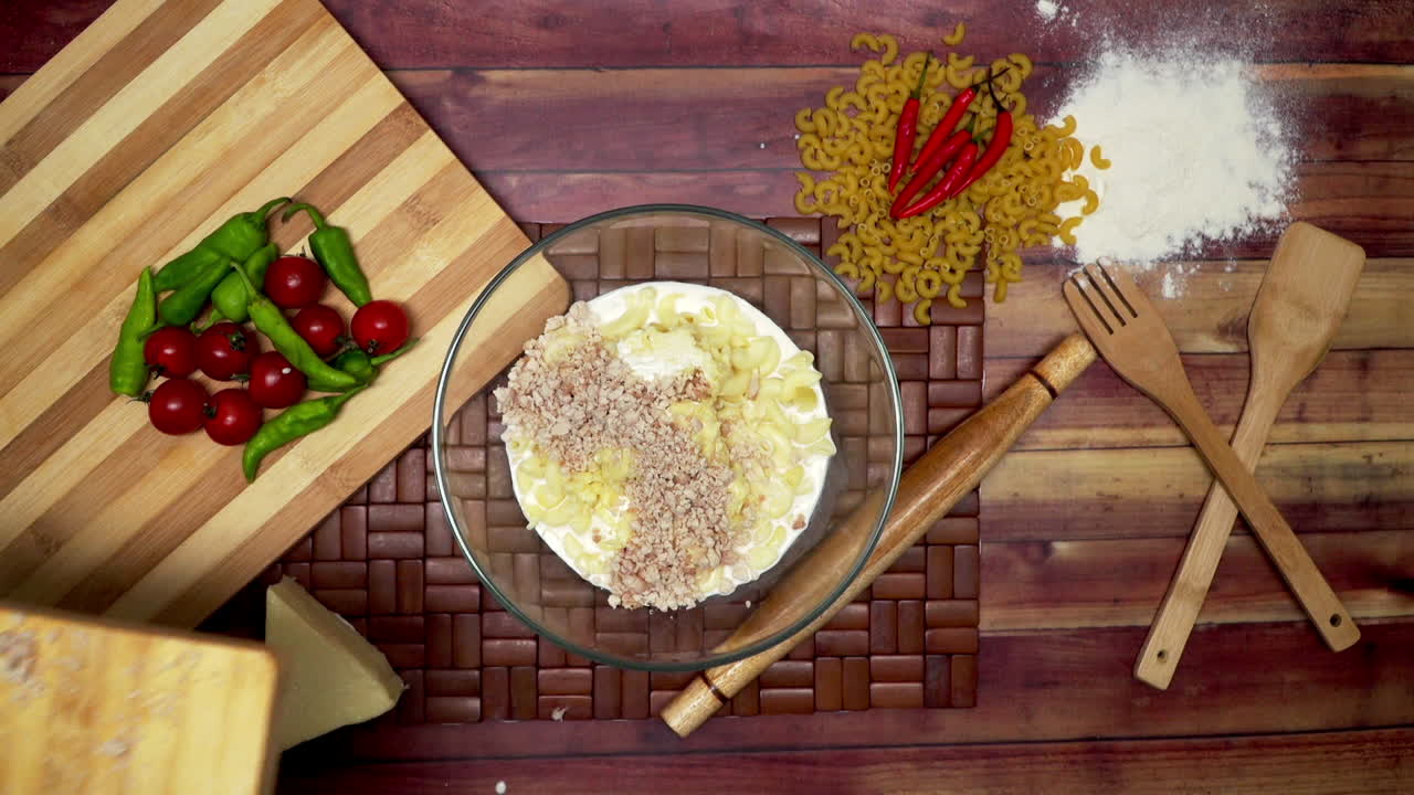 마카로니에 다진 고기, 그릇에 절인 마카로니, 생 마카로니, 나무 숟가락, 나무 주걱, 밀가루, 롤링 핀 및 칠리를 테이블에 추가하는 상위 뷰