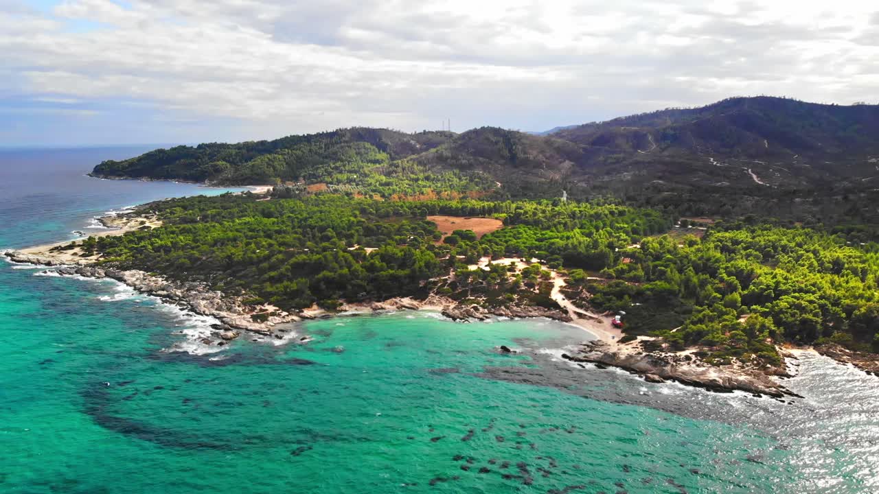 Aerial drone view of the Aegean sea rocky coast with blue transparent water, multiple greenery, hills. Greece