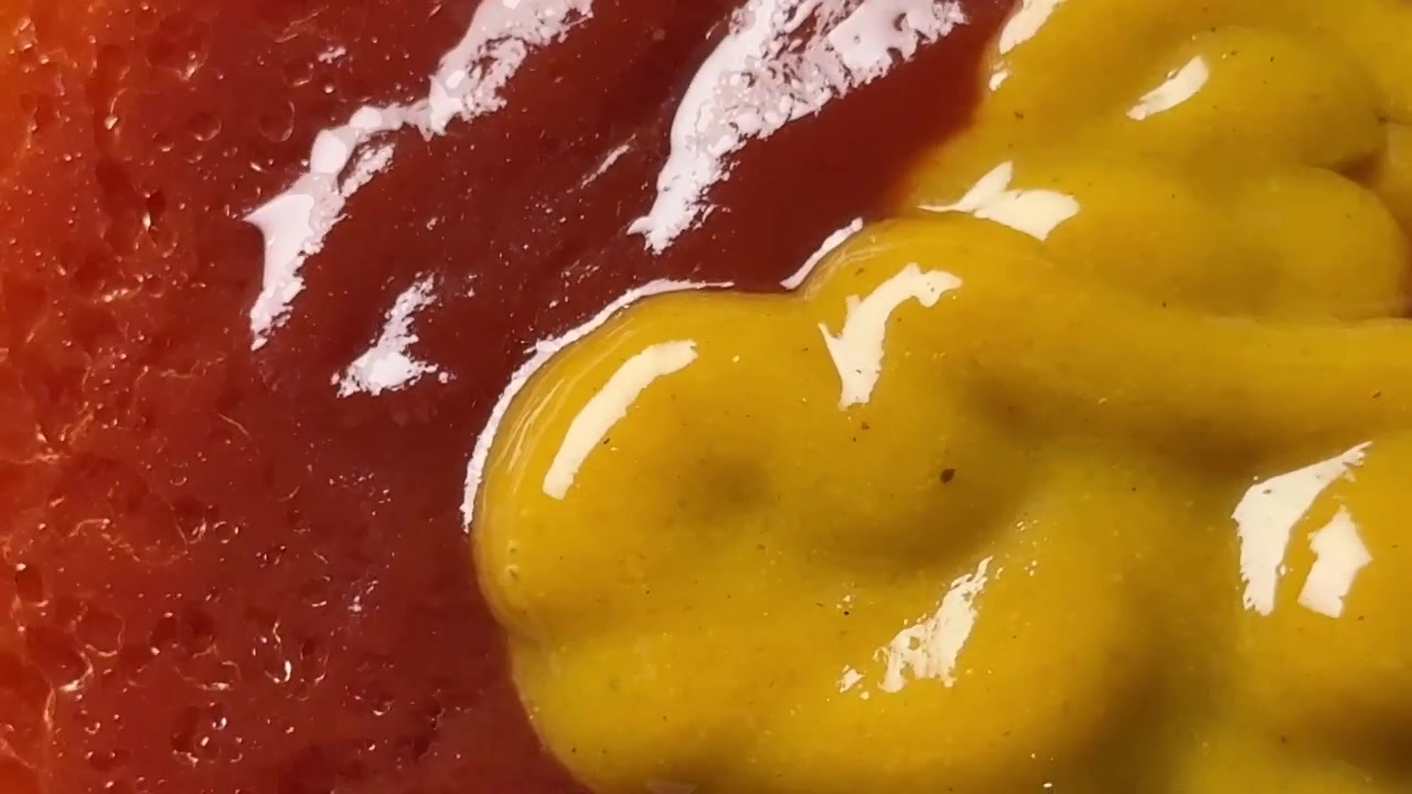 Spremere senape gialla su ketchup rosso