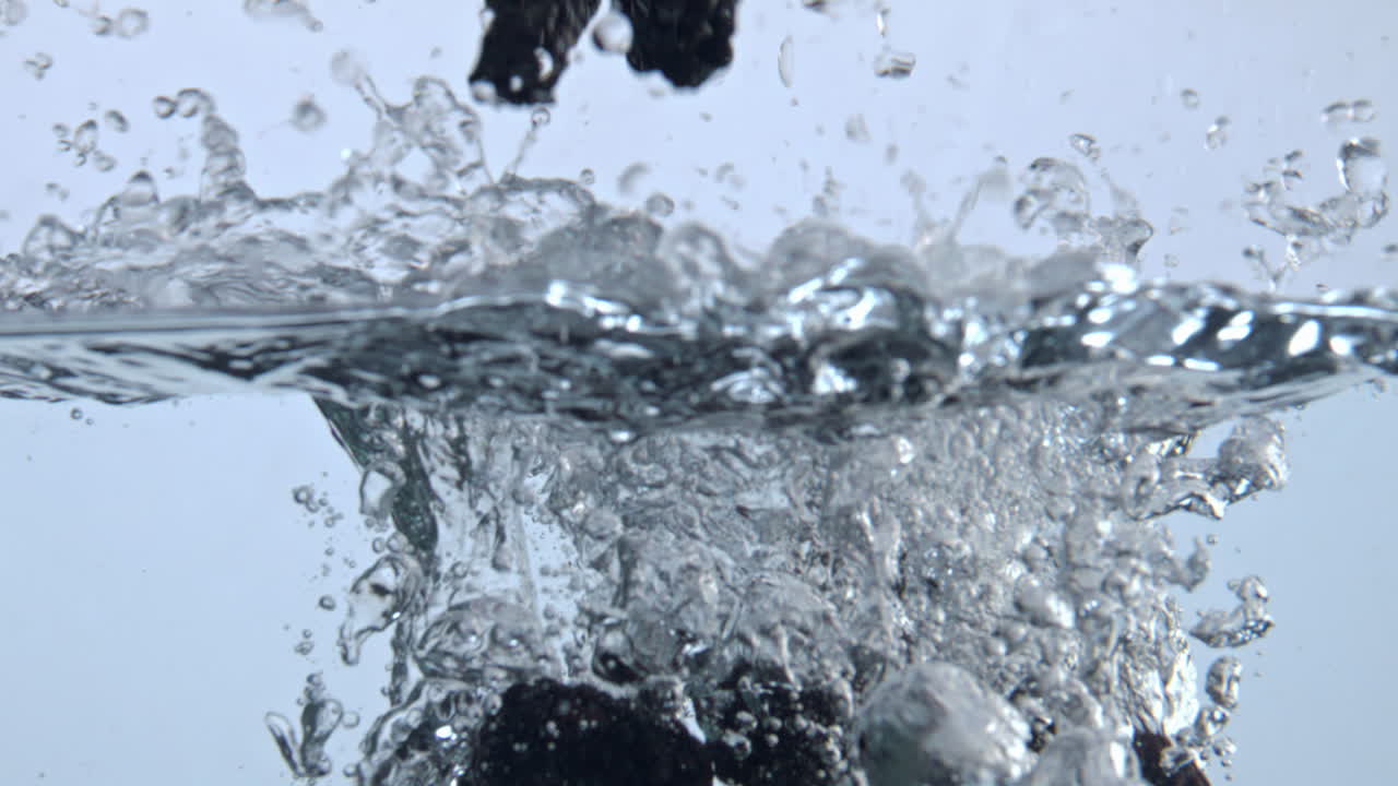 Tasty berries splashing inside aqua closeup. Bramble floating transparent water
