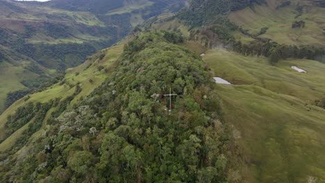 a drone pullback from hidden crosses in green mountains surrounding jardín, colombia, with a cloudy sky backdrop