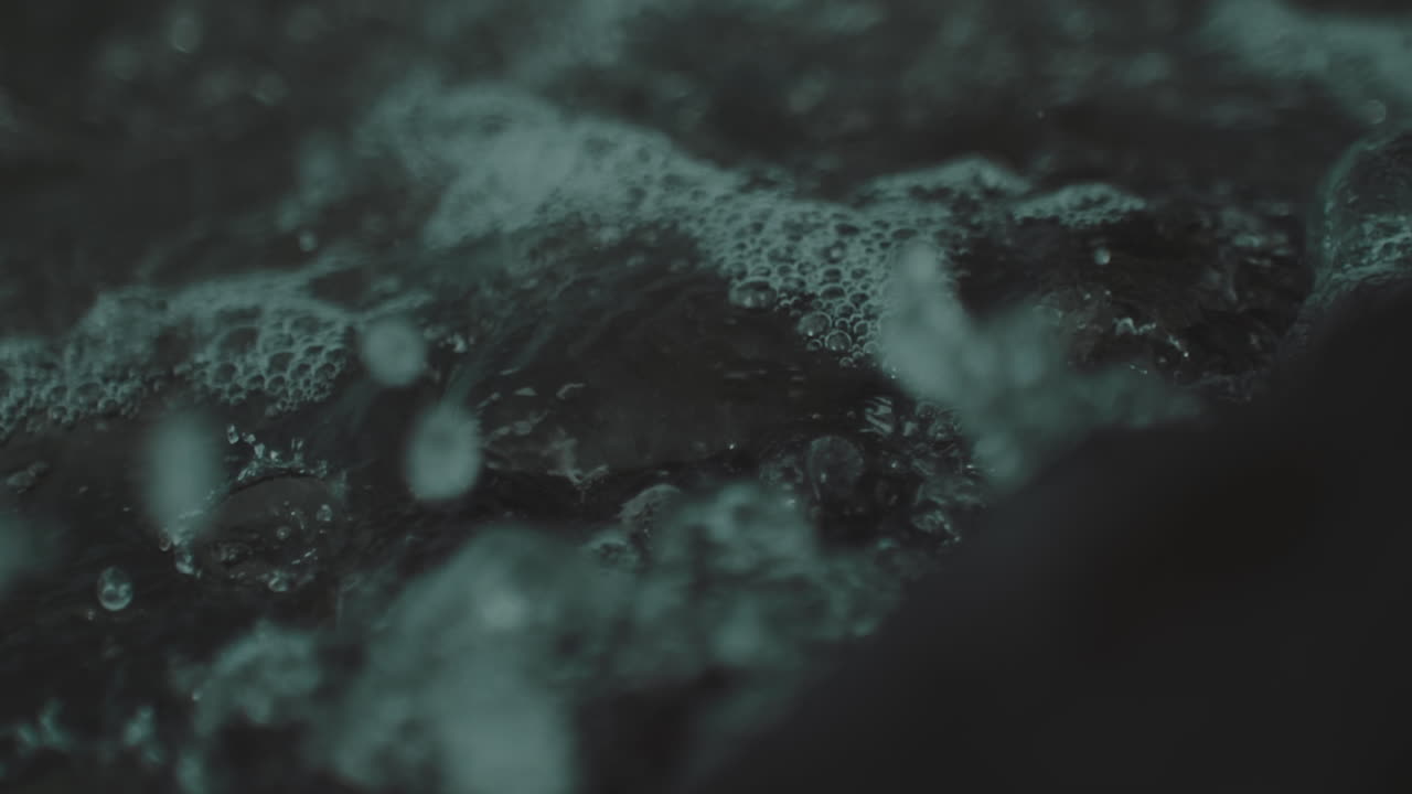 primer plano de aguas claras tormentosas chocando contra rocas dentadas en un día tormentoso oscuro y sombrío