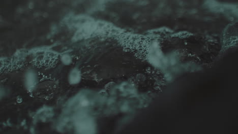 Closeup-of-clear-stormy-water-crashing-against-jagged-rocks-on-stormy-dark-gloomy-day