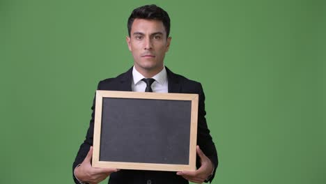 young handsome hispanic businessman against green background