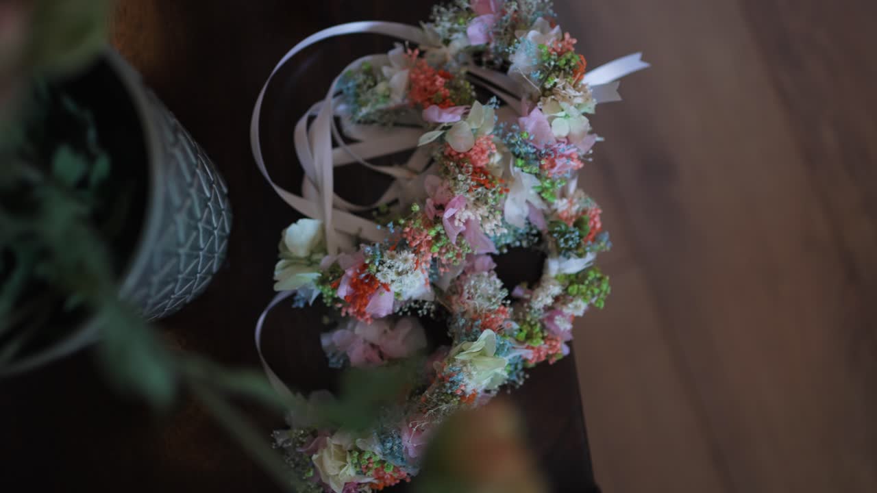 delicate floral wedding crowns with pastel ribbons arranged on a dark wooden surface