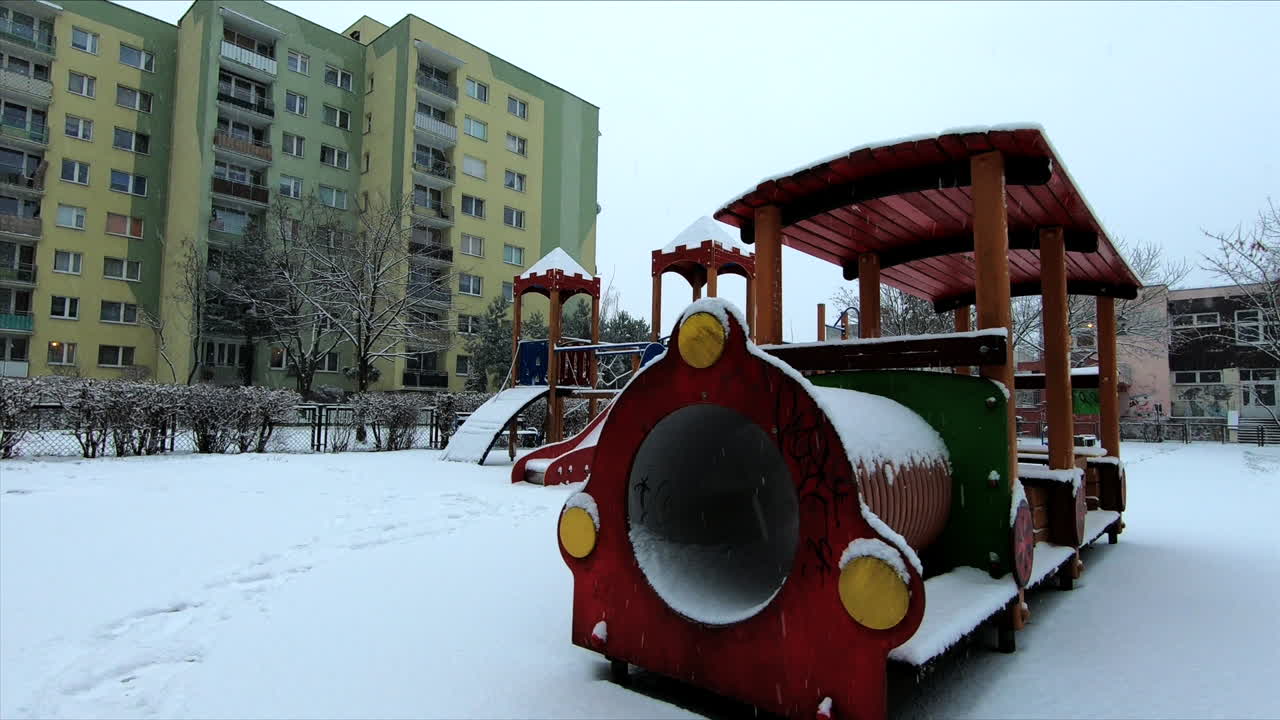 la nieve cae en un pequeño parque infantil en la ciudad