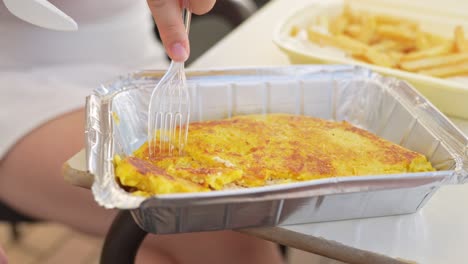 Cutting-omelette-with-cheese-and-meat-in-a-takeout-tray,-close-up