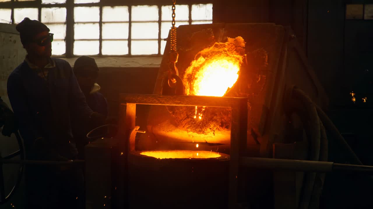 Worker pouring molten metal from container in foundry workshop 4k
