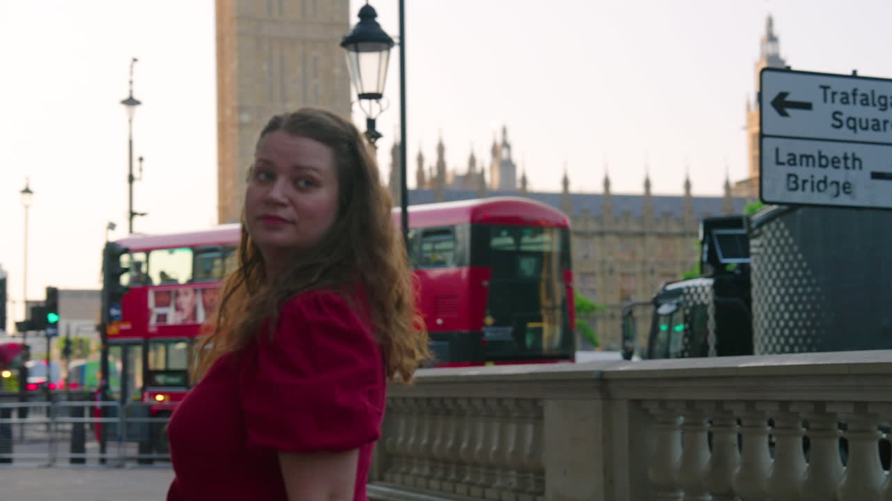 Tourist Wearing Dress On The Street With A Red Phone Booth And Double-Decker Bus In London, England, UK. Rotating Shot
