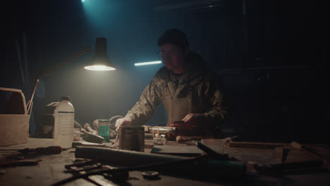 a bombmaker assembles a bomb in his workshop at night