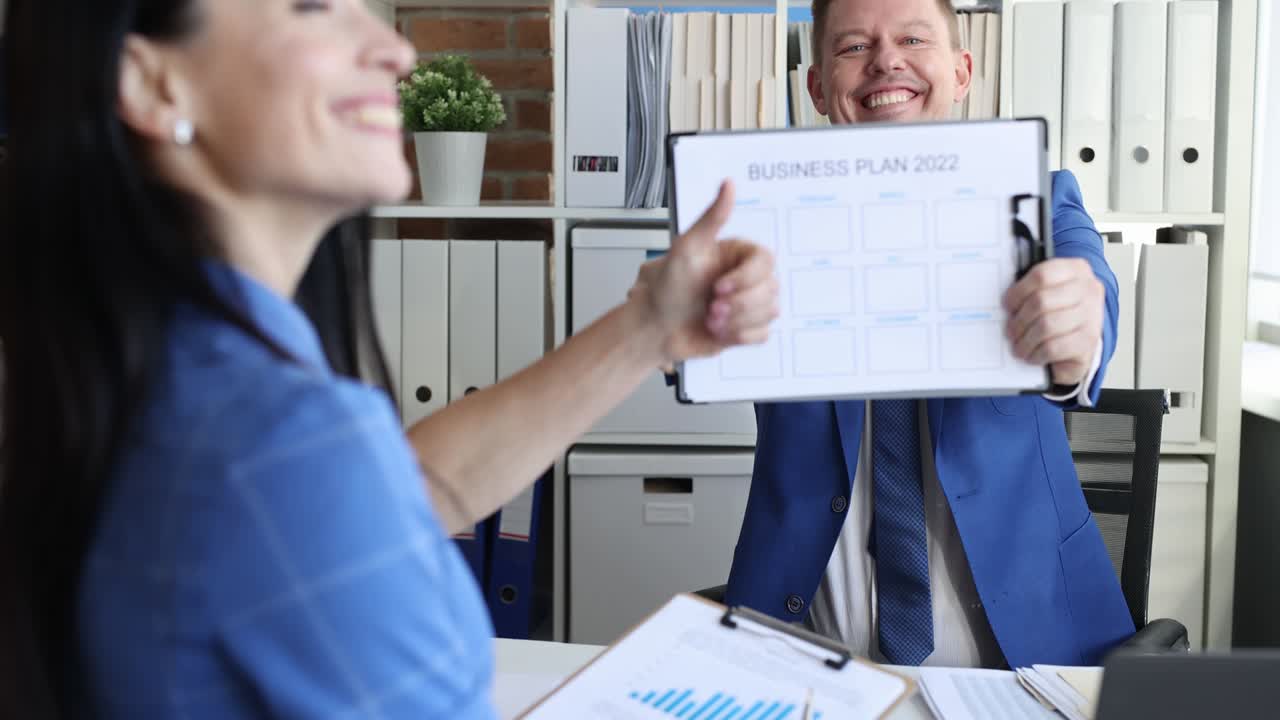 hombre mostrando documento de plan de negocios para 2022. mujer mostrando el pulgar hacia arriba película 4k en cámara lenta