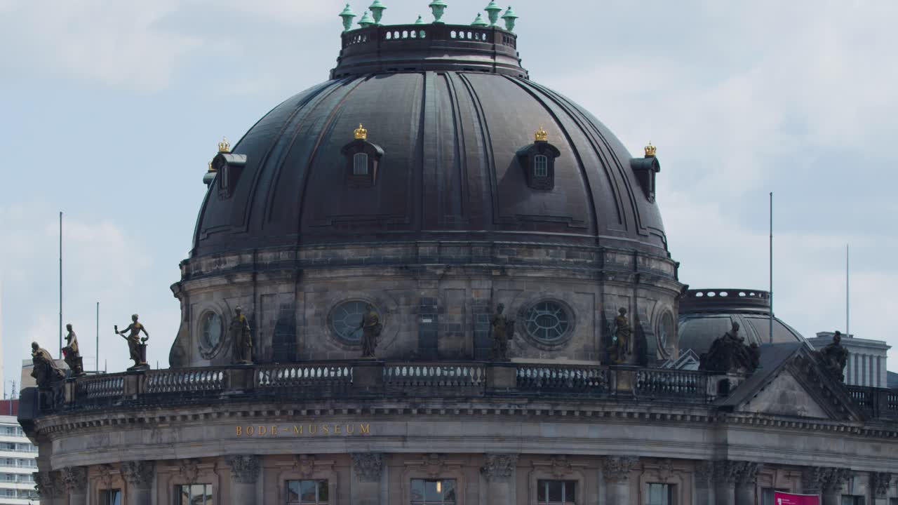 Camera glides toward Bode Museum, passing under bridge on sunny day with soft daylight