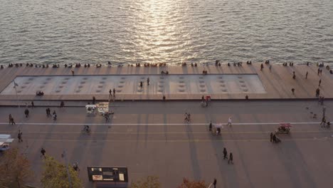 aerial - people passing by in thessaloniki seaside walkway at sunset