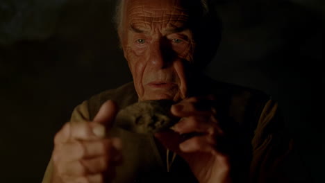 an old man examines an ancient artifact