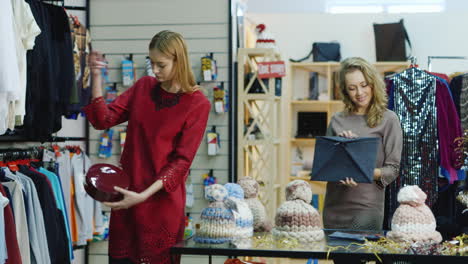 Two-Young-Female-Customers-Choose-Clothes-In-Shop