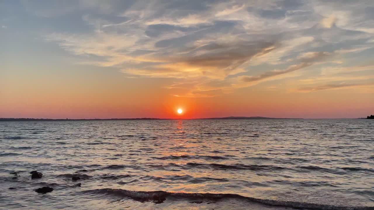 수평선 너머로 해가 지는 잔잔한 파도