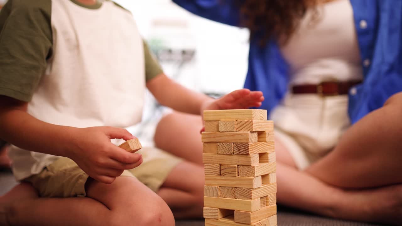 Anonymous mother and son playing tower block game at home