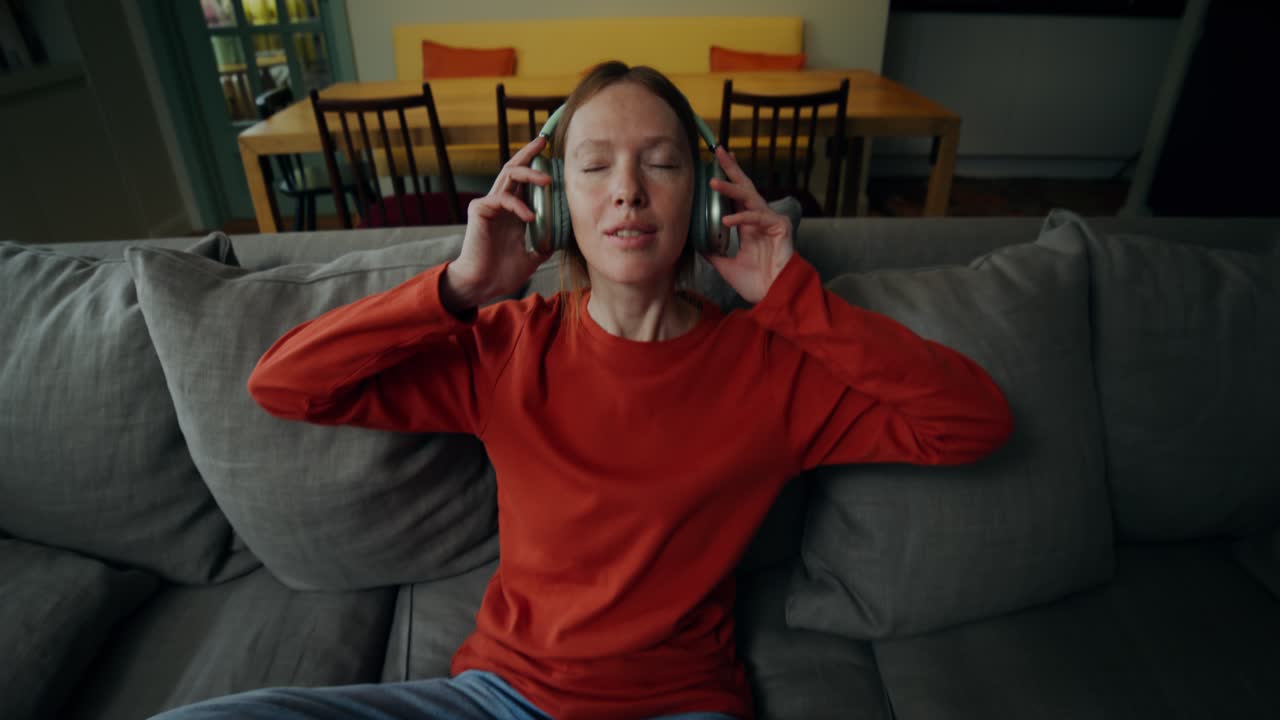 여성이 헤드폰으로 소파에서 휴식을 취하고 있습니다.
