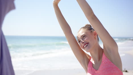 young caucasian woman stretches her arms up on a sunny beach