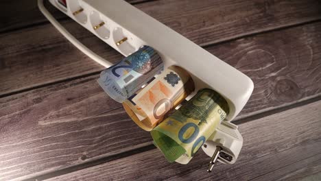 un primer plano de dinero dentro de un enchufe eléctrico. concepto de altos precios.