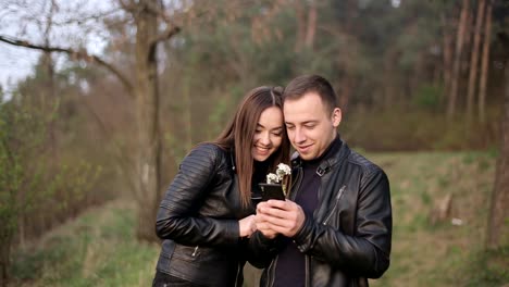 couple looking at smartphone outdoors with flowers