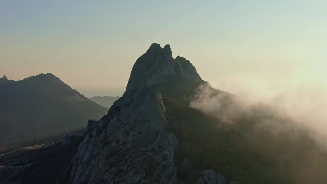 vuelo de avión no tripulado sobre la cima de una montaña donde los árboles crecen y la niebla se arrastra en un día soleado de otoño toma aérea