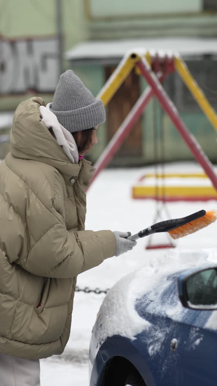 mujer quitando la nieve del coche en invierno