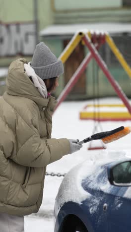 woman removing snow from car in winter