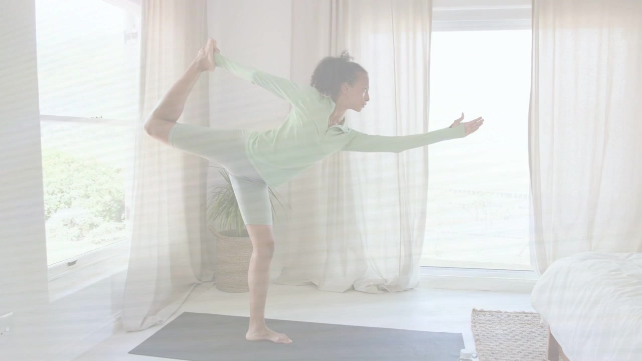 Woman raising arms, shifting weight and pulling left foot on yoga mat for fitness balance