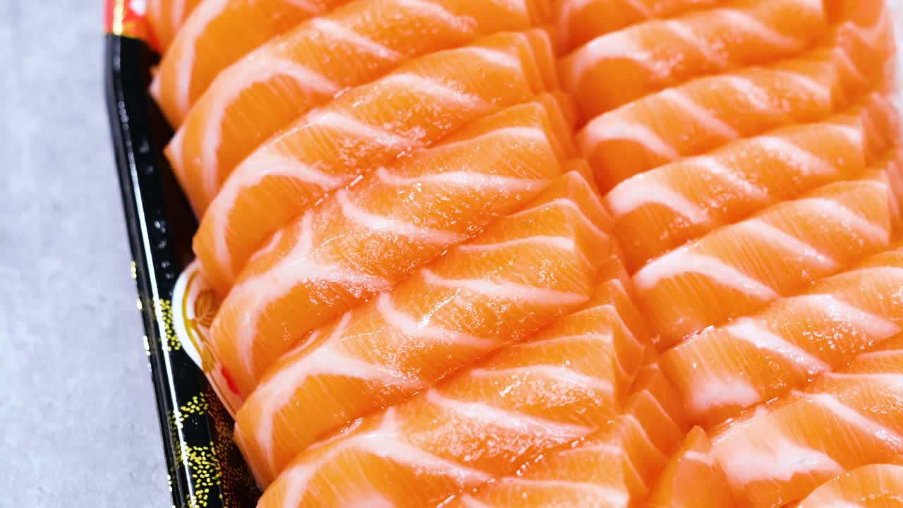 Primo piano in rotazione di sashimi di salmone su piatto, cibo giapponese.