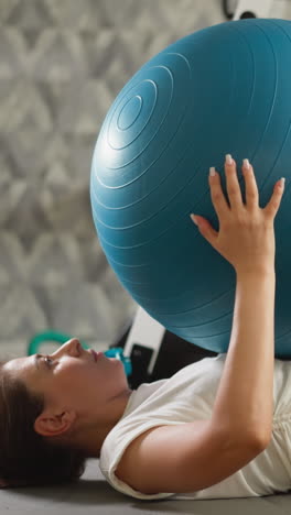 mujer hace entrenamiento de abdominales con fit-ball en casa. dama atlética hace abdominales sosteniendo una pelota grande en el suelo del gimnasio doméstico. deportista se sienta levantando la pelota