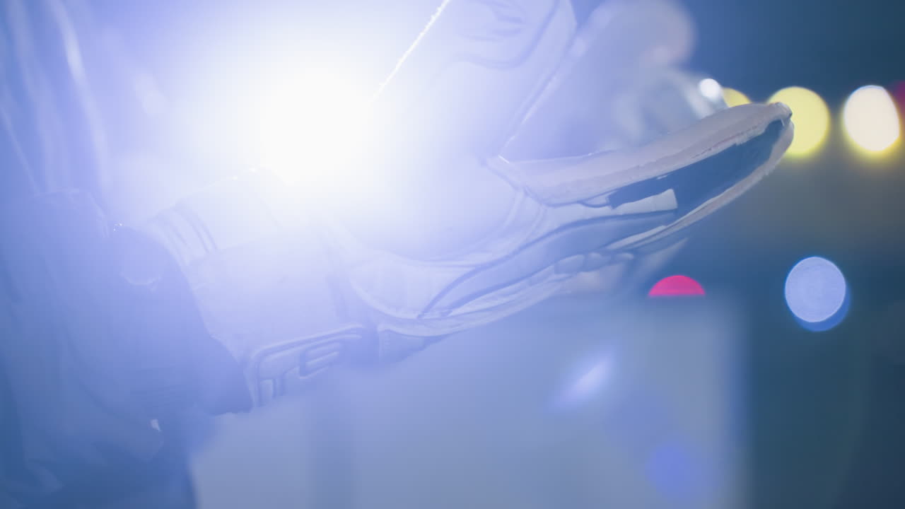 장갑을 쓴 손이 주먹으로 히는 극단적인 클로즈업, 흐릿한 보케 빛의 배경으로 장갑의 질감과 세부 사항을 강조합니다.