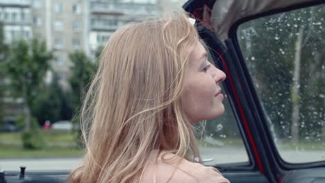 woman in a vintage convertible on a rainy day