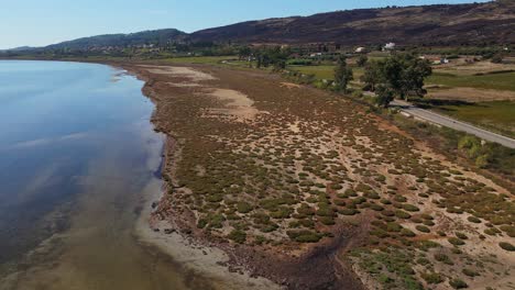 drone flying across swampy sand bank and a shallow part of the ionian sea between lixouri and livadi with mountains in the background