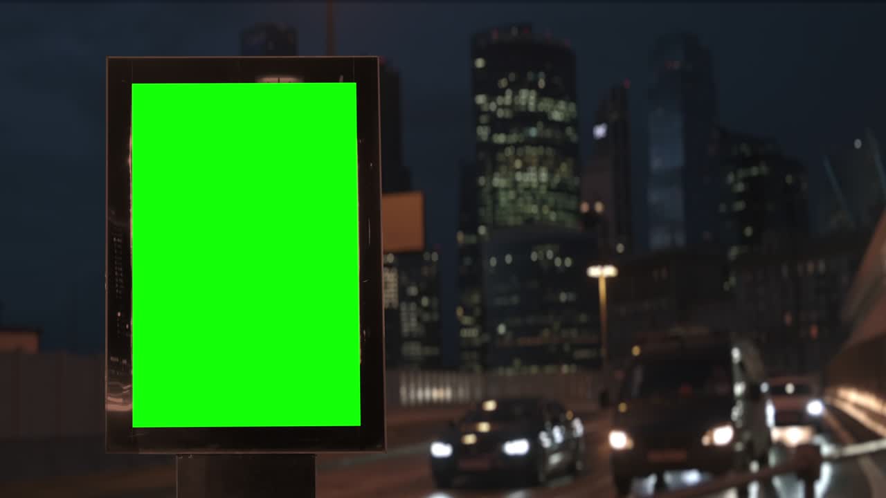 Cartellone pubblicitario con schermo verde su un'autostrada trafficata con traffico, luci al neon