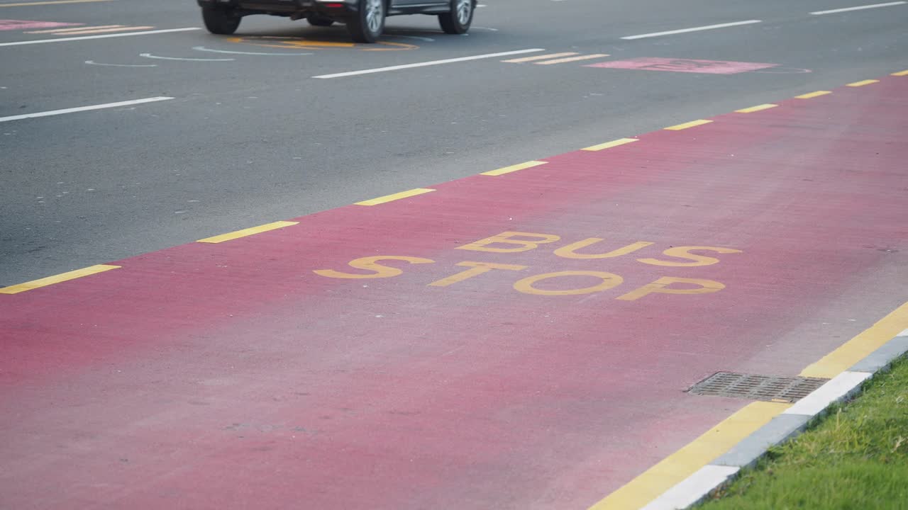 A bus stop lane with painted text on a city road, featuring moving vehicles