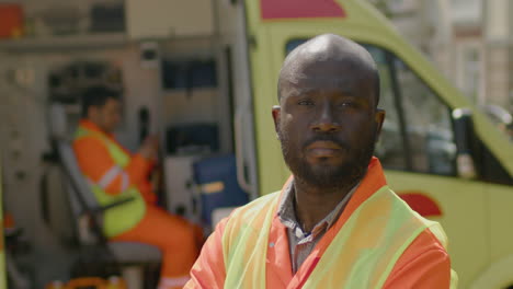 black male ambulance driver with crossed arms at the street