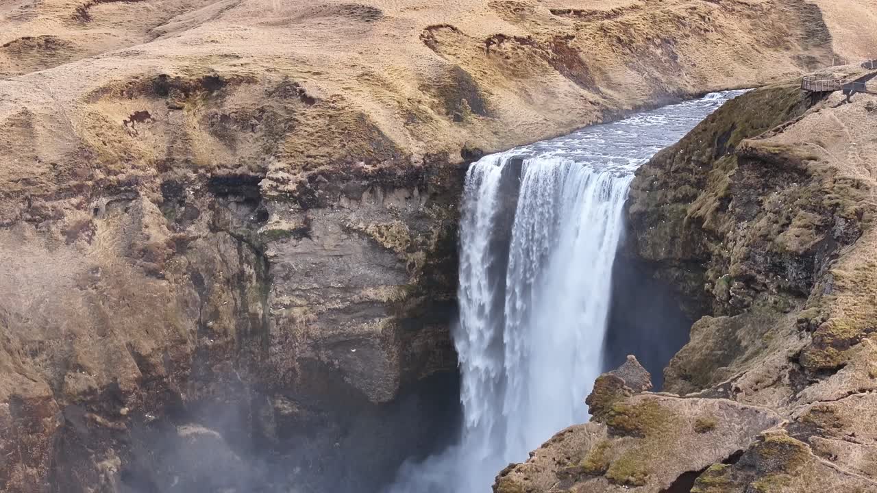 Aerial view of Skógafoss waterfall in South Iceland, where the Skógá River plunges over cliffs near the Eyjafjallajökull volcano. Surrounded by rugged hills, natural wonders and a tourist destination.