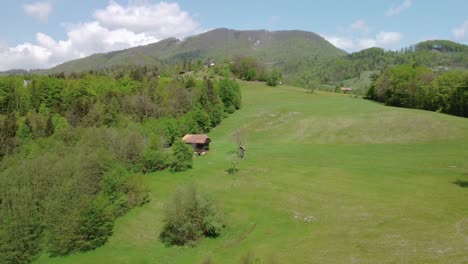 Flying-beside-green-countryside-hills-and-old-barn,-farmland-in-the-spring