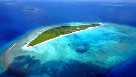 Luftbild-Aus-Großer-Höhe-Einer-Mit-Palmen-Bedeckten-Insel-Auf-Den-Malediven,-Während-Die-Farbe-Des-Meeres-Von-Türkis-Zu-Dunkelblau-Wechselt