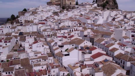 tilt up shot of olvera city spain with white houses and orange roofs, aerial