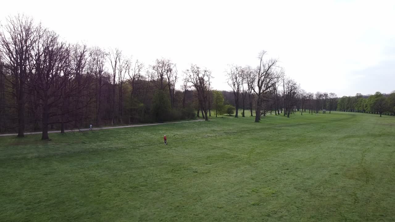 threatening shot of a person walking their dog in a large park