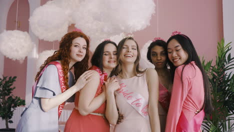 front view of bachelor girl and her friends wearing bride to be sashs and headdresses posing at camera