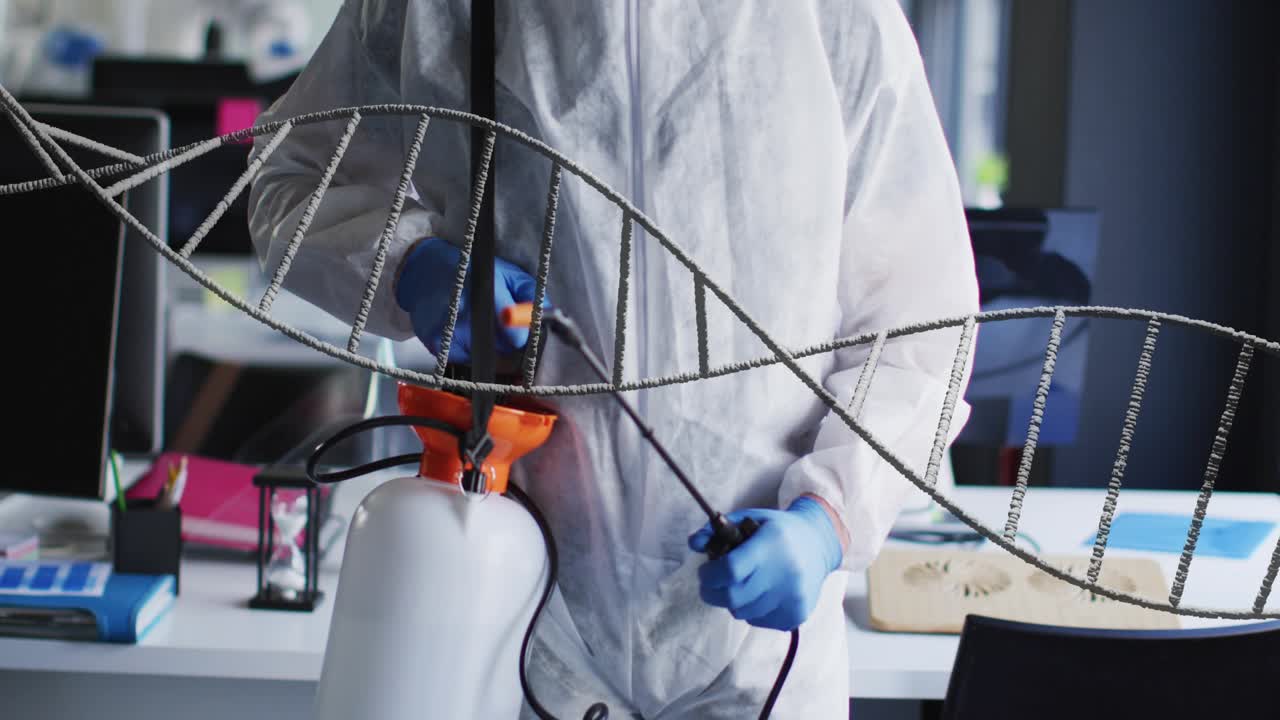 Male technician gripping sprayer and adjusting nozzle, sanitizing laboratory while DNA helix floats