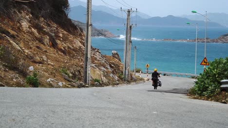Travel-on-motorcycle-with-kitesurfing-equipment-along-azure-sea,-Vietnam-coast