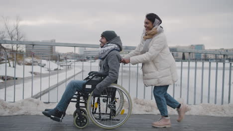 side view of a muslim woman pushing friend on a wheelchair on a slope 1