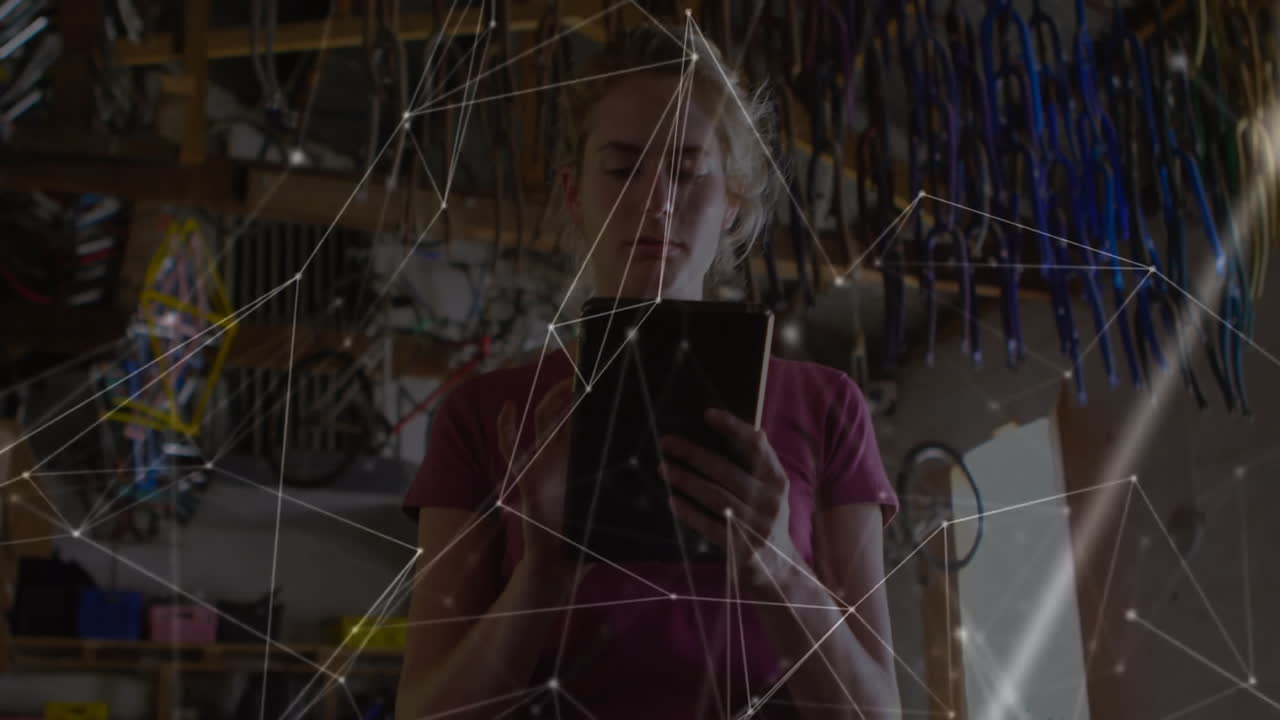 female mechanic reviewing tablet in workshop, displaying technology network lines over tools