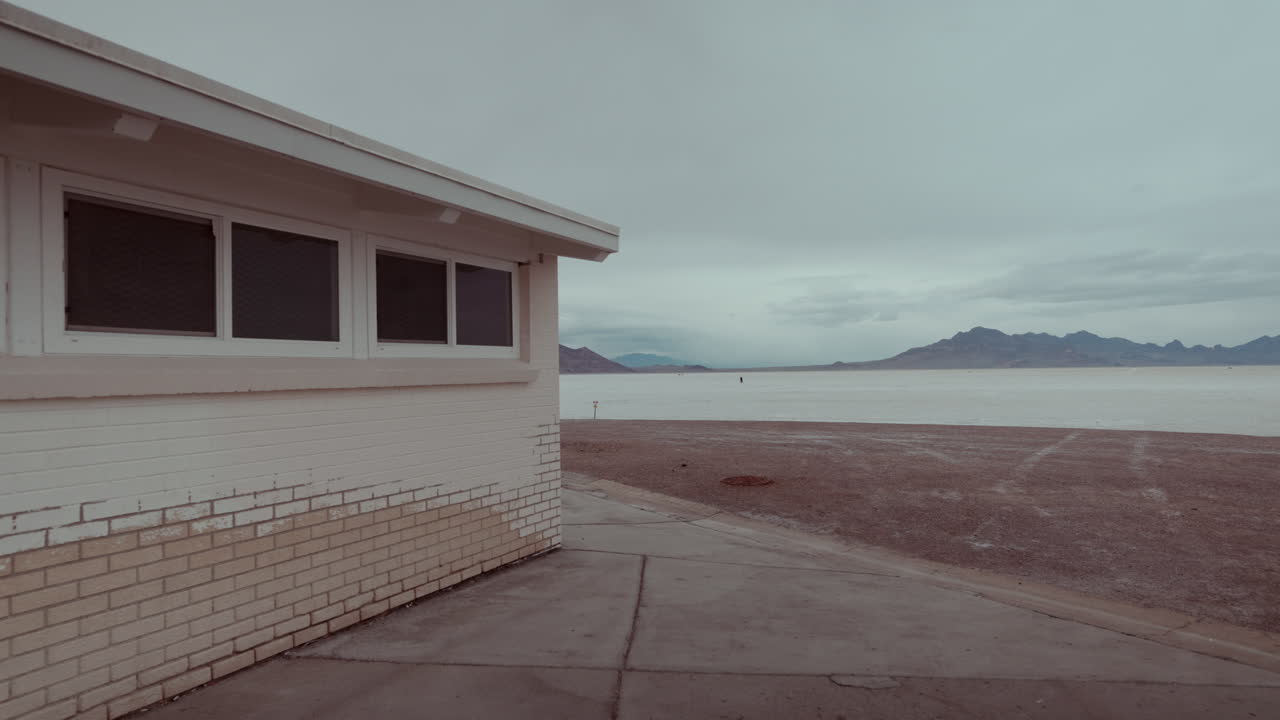 A small white building overlooking a vast salt flat in a desert landscape.