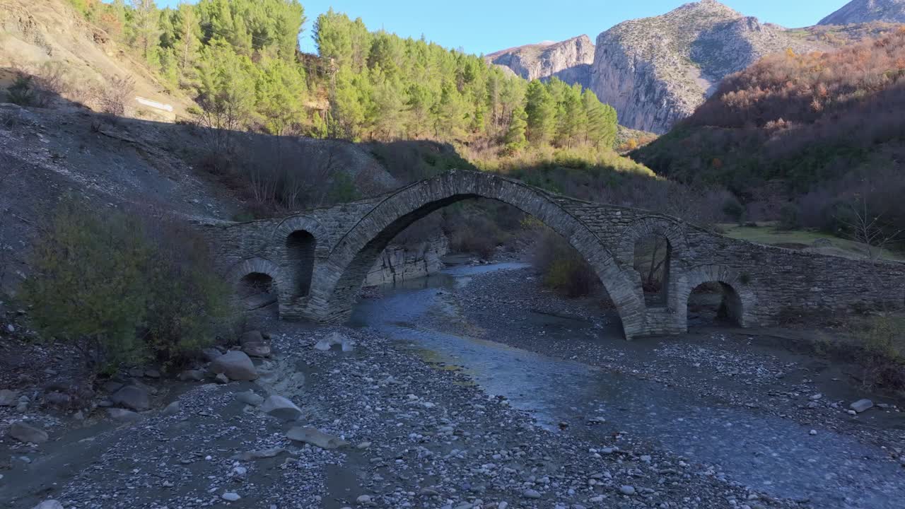 Imagem de drone da Ponte Ura e Kasabashit atravessando um rio tranquilo, Albânia.